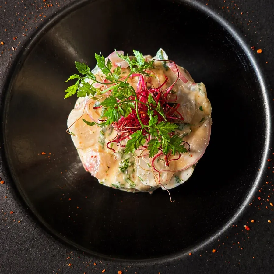 Un ceviche aux herbes fraîches, servi en assiette creuse noire
