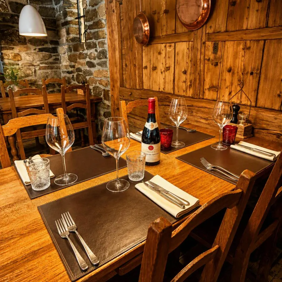 Une table dressée pour le soir, contre le mur de pierre