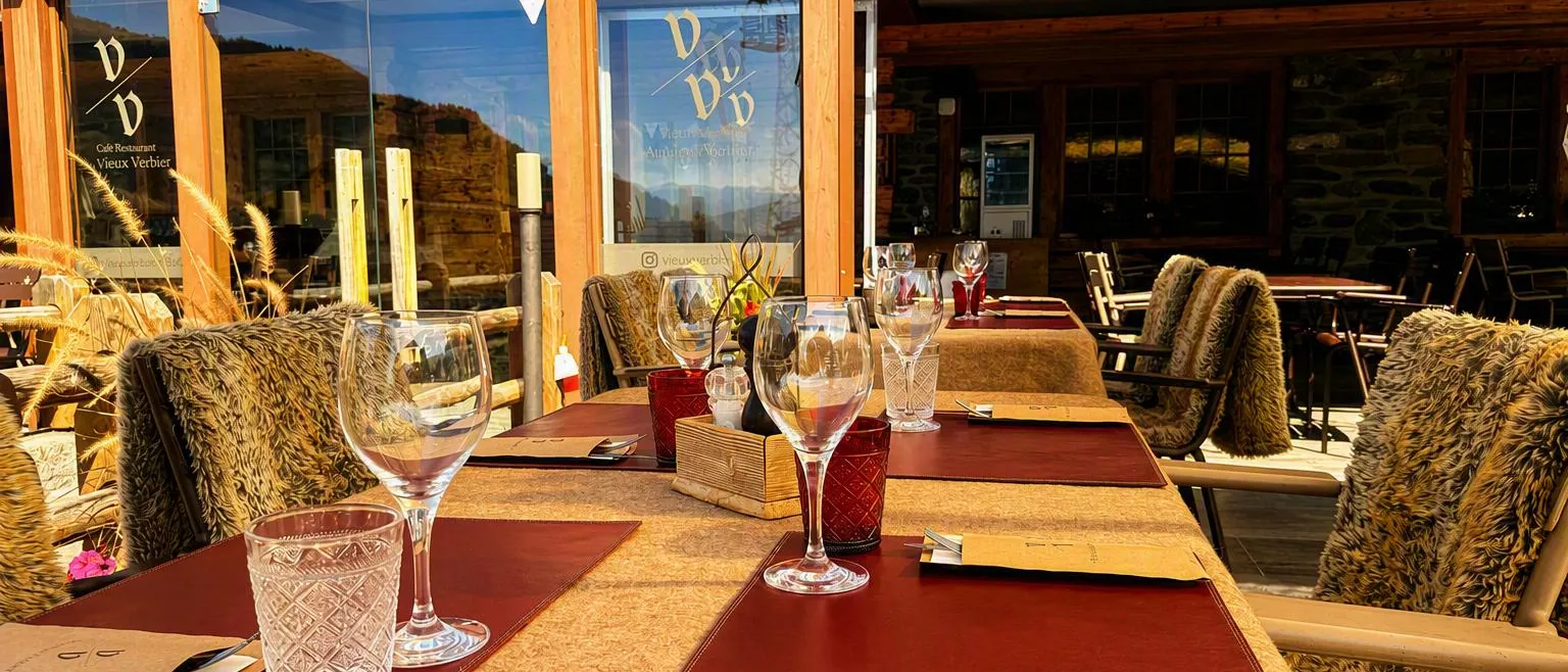 La terrasse couverte au soleil couchant, tables dressées et peaux sur les chaises