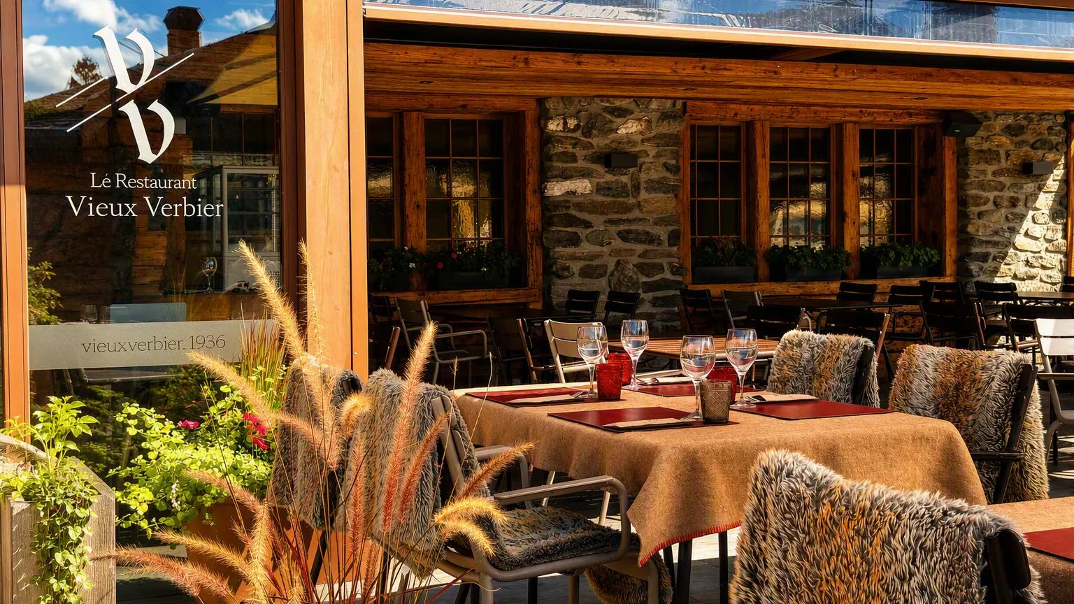 La terrasse du restaurant, le monogramme gravé sur la vitre et le mur de pierre